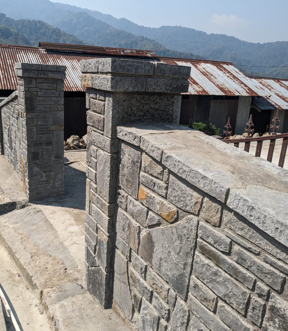 Stone gate and traditional buildings with corrugated roofs in Dzüleke